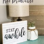 Stay Awhile sign with lamp and vase on end table