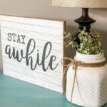Stay Awhile sign on end table with lamp